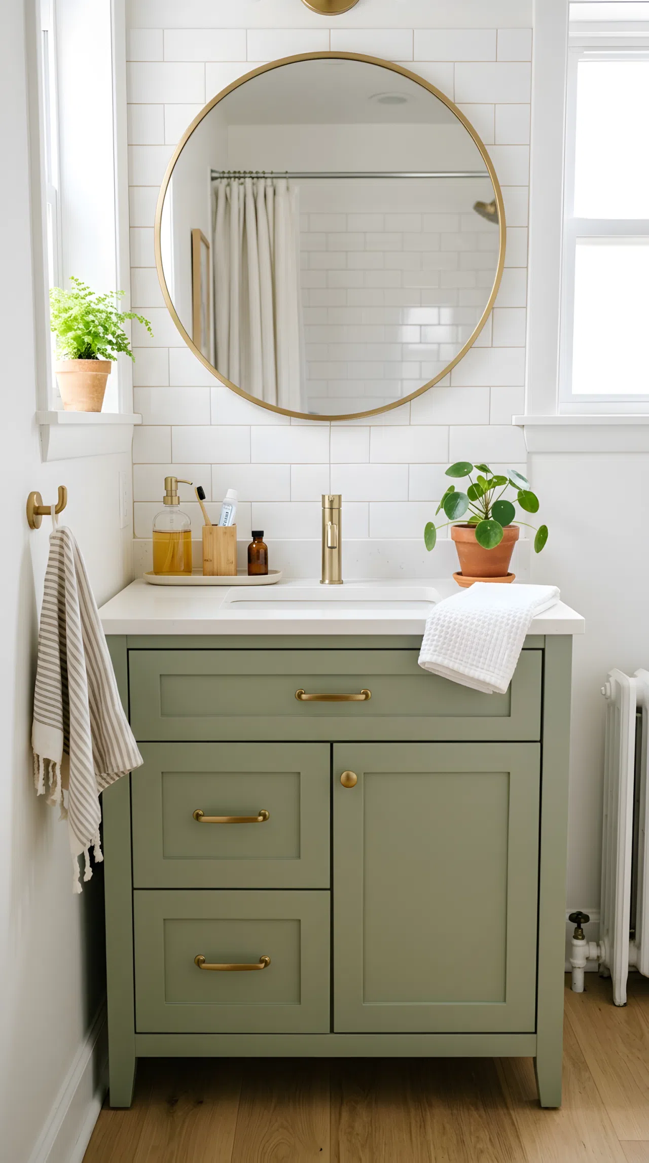 Real-life photo of a small apartment bathroom vanity painted in sage green (RGB 158,169,133), brass cabinet hardware, neatly arranged bathroom essentials, clean organized counter, bright natural light, vibrant fresh tones, stock photography style.