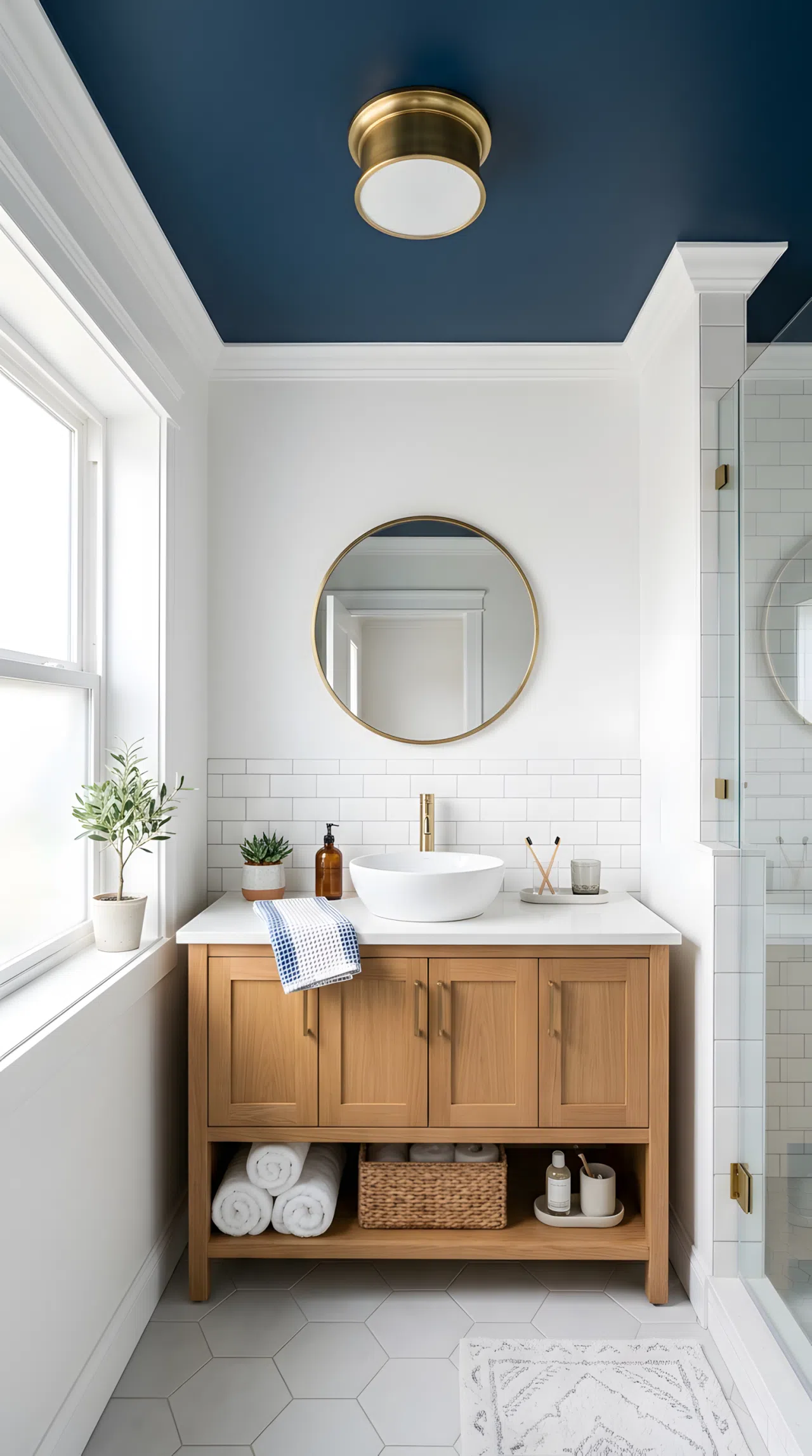 A real-life bathroom photo with a deep blue painted ceiling (RGB 20,40,80) above crisp white walls and trim, neatly made vanity below, beautifully arranged, organized, clean, bright natural light bouncing softly off the matte ceiling, vibrant color, photographic stock-photo style.