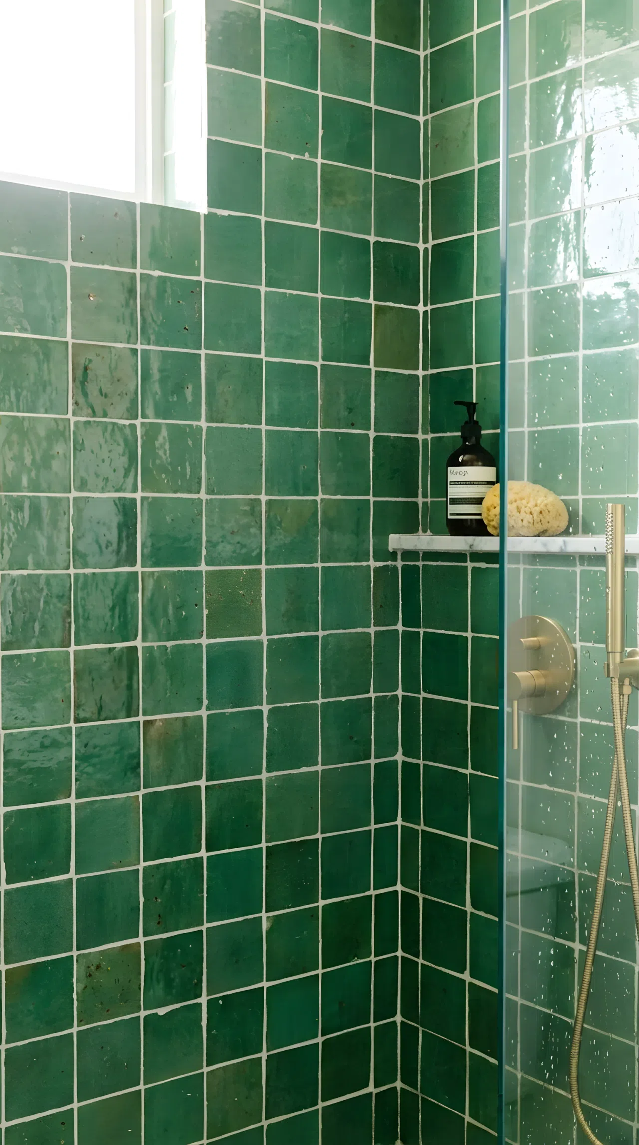 Real-life photo close-up of a shower stall lined with handmade zellige tile in mid-tone green (RGB 90,120,90), irregular glazed texture, white grout, beautifully arranged, clean, bright natural light, vibrant color, stock photography style