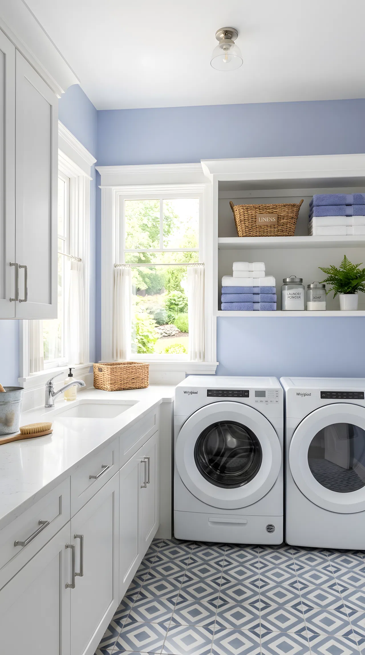 Real-life photograph of a laundry room with icy periwinkle painted walls, white cabinetry, silver hardware, geometric patterned tile floor, folded white and blue towels neatly arranged on open shelving, bright natural light flooding in through a window, clean and organized space, vibrant fresh periwinkle tones, stock photo style, no people