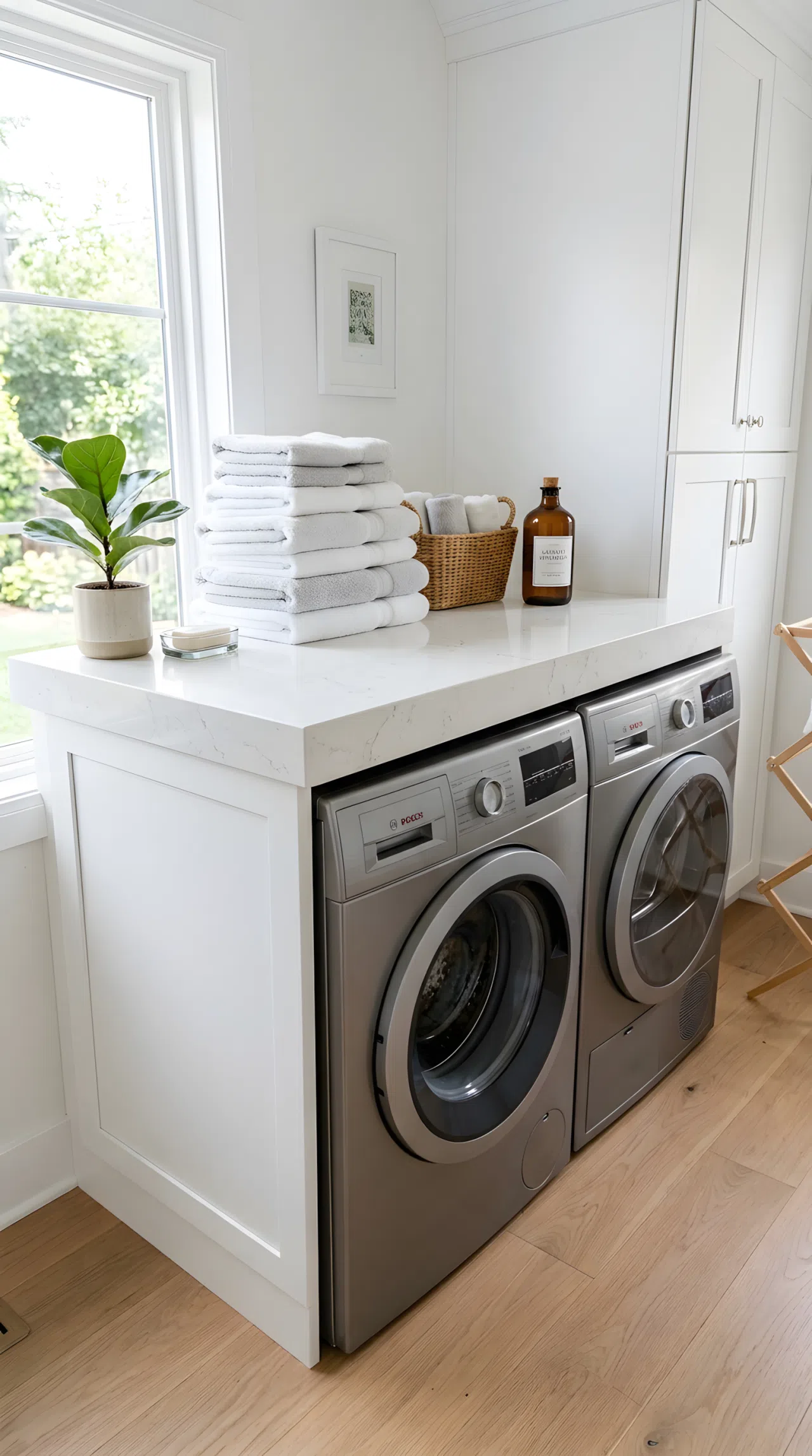 A real-life photo of a floating white quartz countertop mounted above stacked front-load washer and dryer units, neatly folded towels resting on top, bright natural light, clean, organized, beautifully arranged, modern minimalist interior.