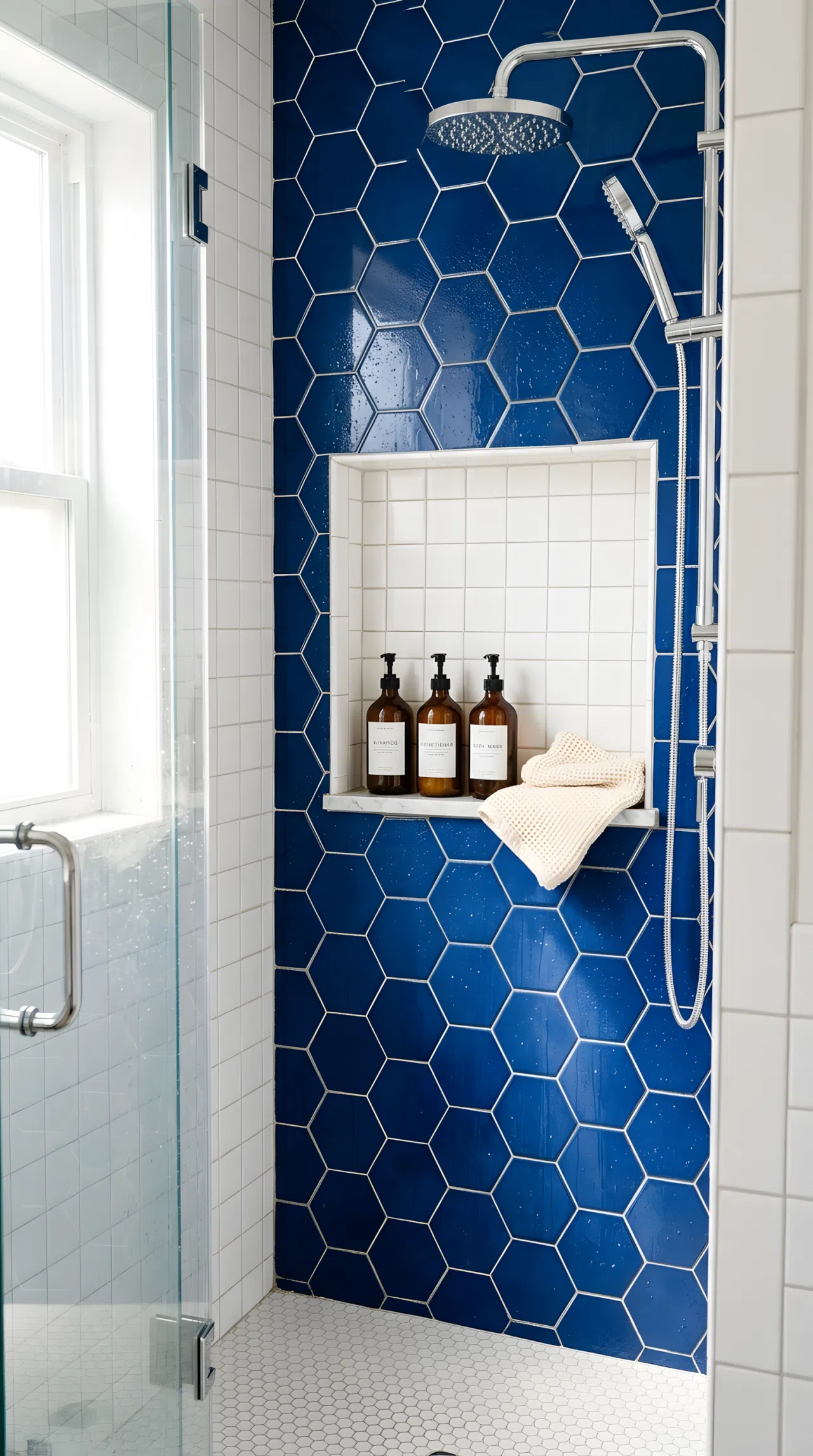 Real-life photo of a small bathroom shower with a recessed tiled niche neatly holding matching bottles and a folded washcloth, beautifully arranged, organized, clean, bright natural light reflecting off wet tile, vibrant contrasting tile color, stock photography, no illustration.